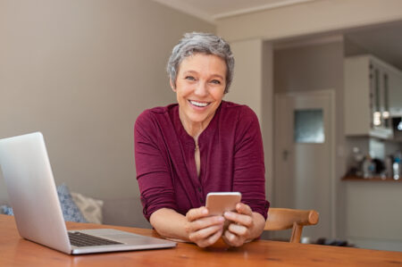 A woman smiles confidently. Implant-supported dentures offer comfort, confidence, and stability often lacking with traditional dentures.
