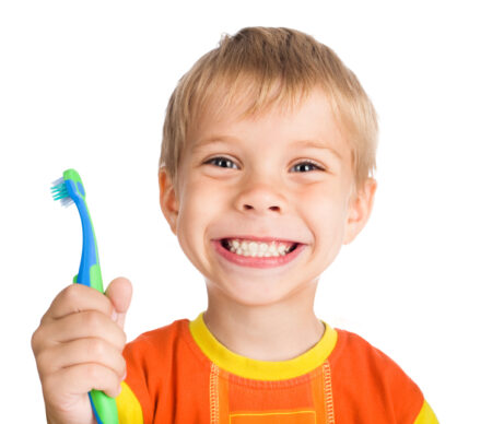 A boy smiles with a toothbrush, as though he has just visited a general or pediatric dentist.