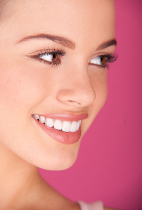 A woman shows a beautiful smile. Regular teeth cleanings promote a healthy smile.